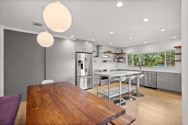 kitchen featuring visible vents, stainless steel appliances, wall chimney range hood, and open shelves