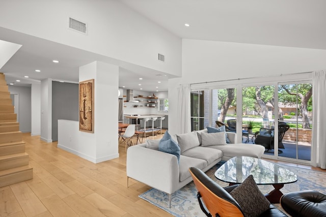 living area featuring light wood finished floors, visible vents, high vaulted ceiling, and a wealth of natural light