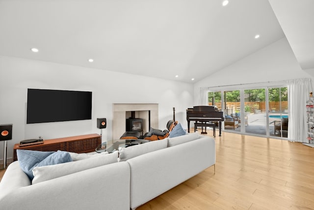 living room featuring recessed lighting, light wood-type flooring, a wood stove, and high vaulted ceiling