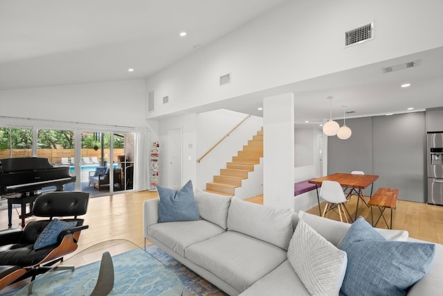 living area featuring light wood-type flooring, visible vents, and stairway