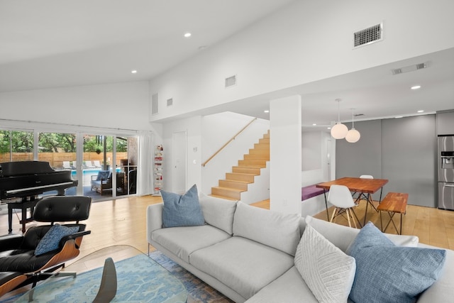 living area featuring visible vents, high vaulted ceiling, and light wood-style floors