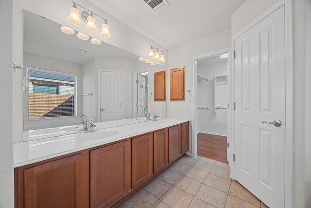 bathroom with a sink, visible vents, double vanity, and tile patterned flooring