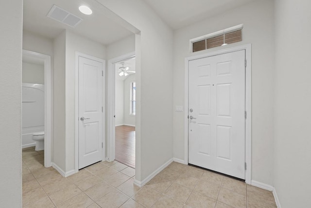 foyer with light tile patterned flooring, visible vents, a ceiling fan, and baseboards