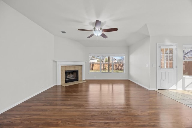 unfurnished living room with visible vents, lofted ceiling, wood finished floors, and a tiled fireplace