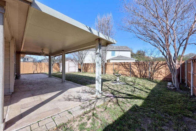 view of yard featuring a storage unit, a fenced backyard, an outdoor structure, and a patio