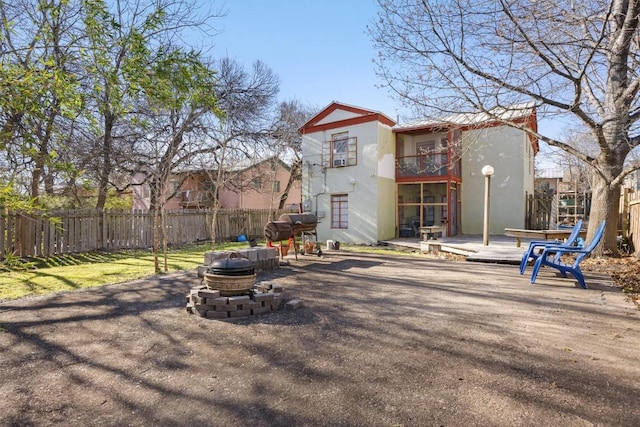 back of property featuring a fire pit, a fenced backyard, and stucco siding