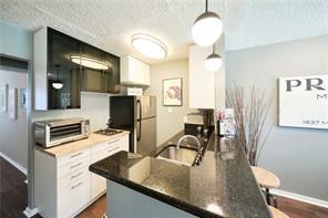 kitchen featuring a sink, a textured ceiling, dark countertops, freestanding refrigerator, and a toaster