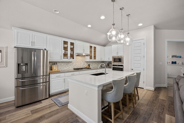 kitchen featuring stainless steel appliances, a sink, wood finished floors, backsplash, and recessed lighting