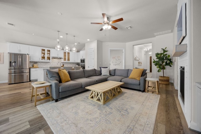 living area with ceiling fan, wood finished floors, a chandelier, recessed lighting, and vaulted ceiling