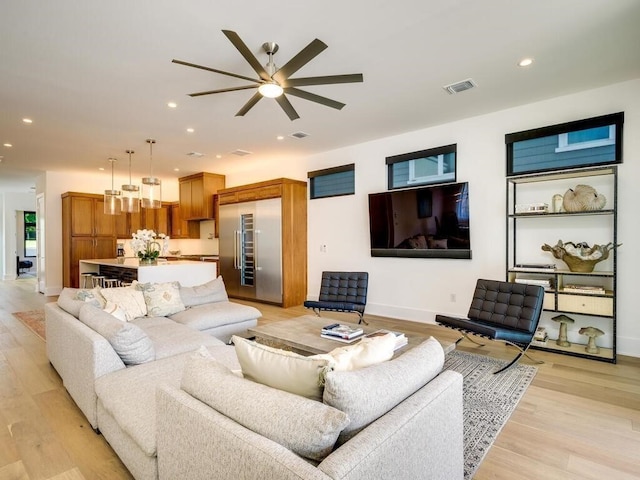 living room with recessed lighting, visible vents, light wood-style flooring, and baseboards