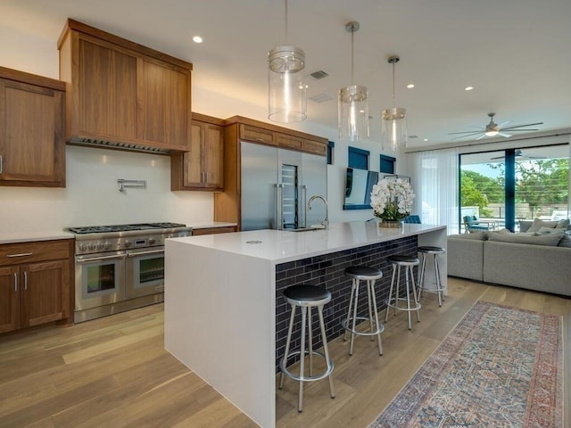 kitchen with light wood-type flooring, brown cabinets, high quality appliances, and open floor plan