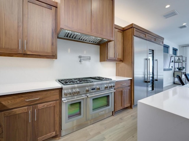 kitchen featuring light wood-type flooring, visible vents, high end appliances, and light countertops