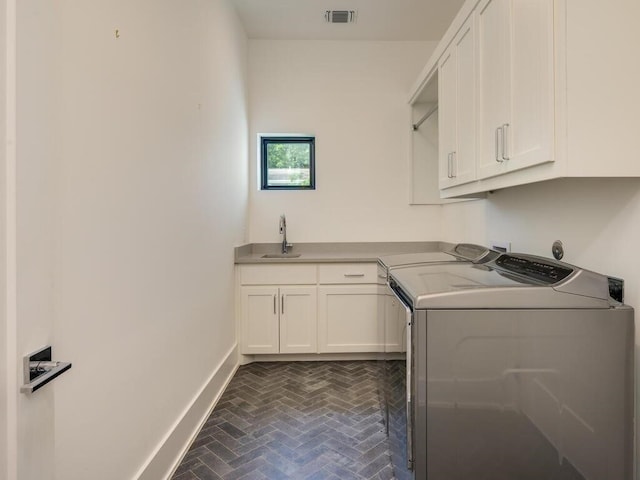 laundry room featuring visible vents, baseboards, brick floor, cabinet space, and a sink