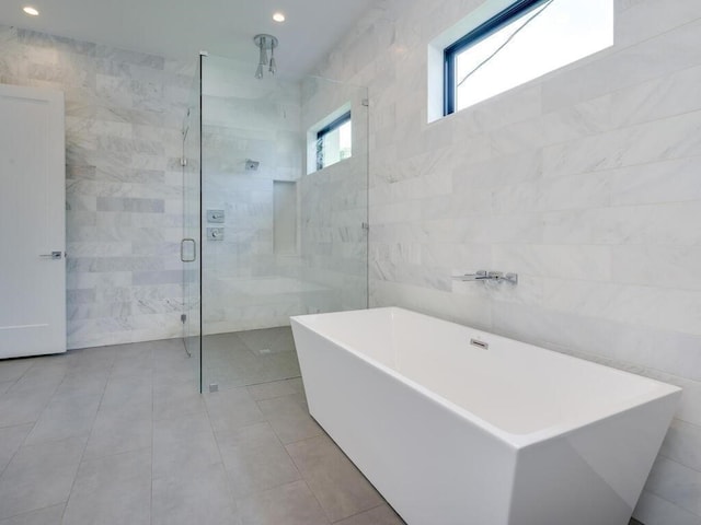 full bathroom with a freestanding bath, tile walls, and a shower stall