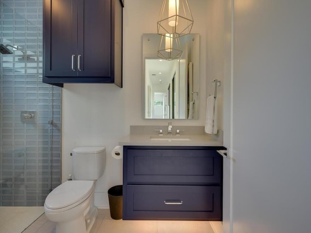 bathroom with vanity, tile patterned floors, toilet, and tiled shower