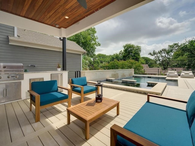 view of patio featuring an outdoor living space, a wooden deck, a grill, and an outdoor kitchen