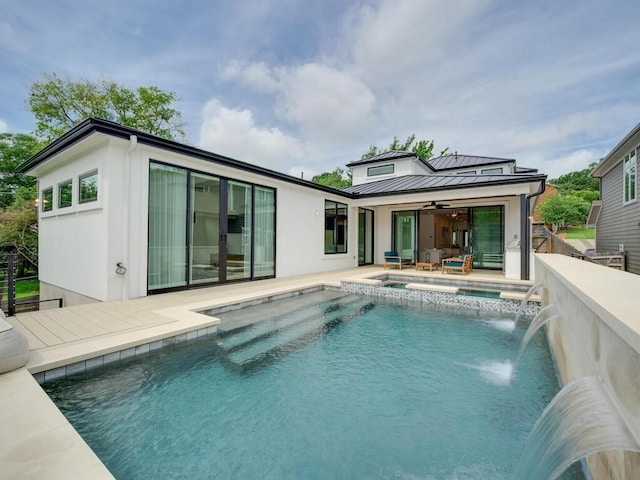 rear view of house with a standing seam roof, an in ground hot tub, an outdoor pool, ceiling fan, and metal roof