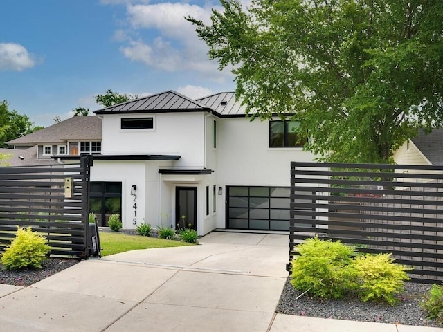 view of front of property with fence, concrete driveway, stucco siding, a garage, and a standing seam roof