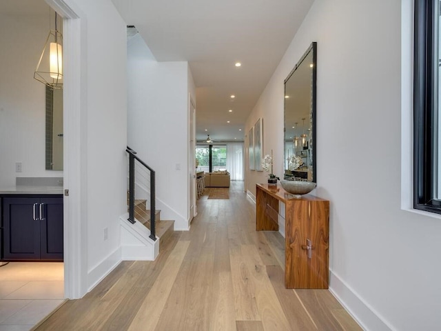 hallway featuring stairway, recessed lighting, baseboards, and light wood-type flooring