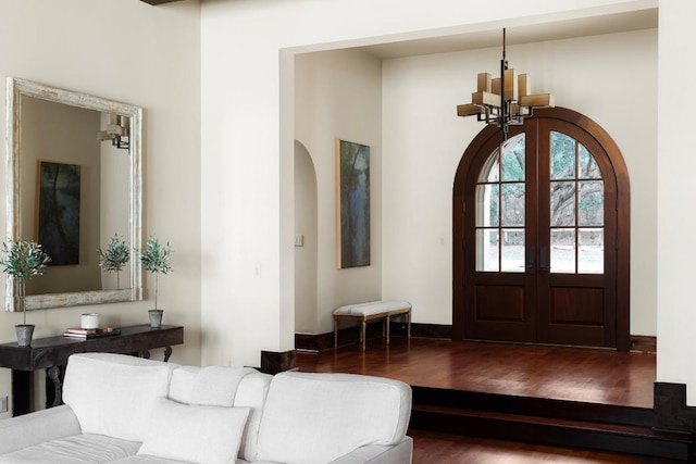 entryway with wood finished floors, baseboards, arched walkways, french doors, and a notable chandelier