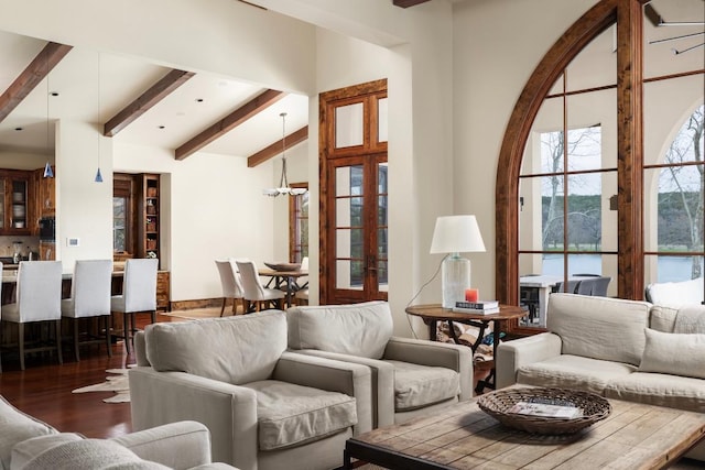 living room featuring a chandelier, lofted ceiling with beams, and wood finished floors