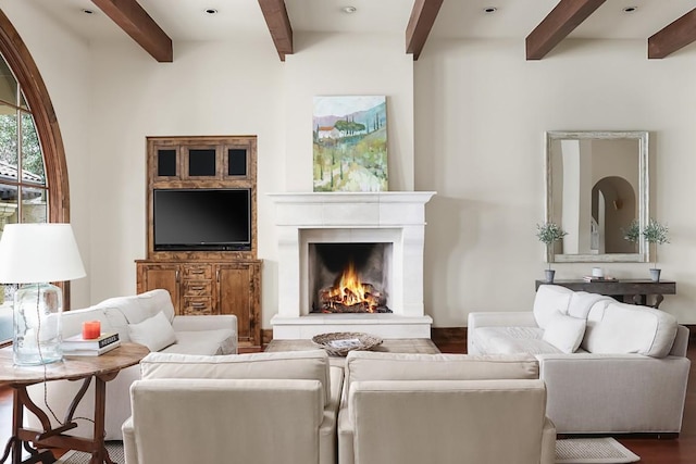 living room featuring beam ceiling, wood finished floors, and a high end fireplace