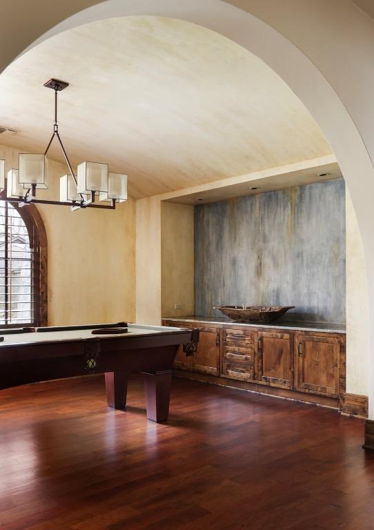 playroom with dark wood-style floors, a notable chandelier, and arched walkways