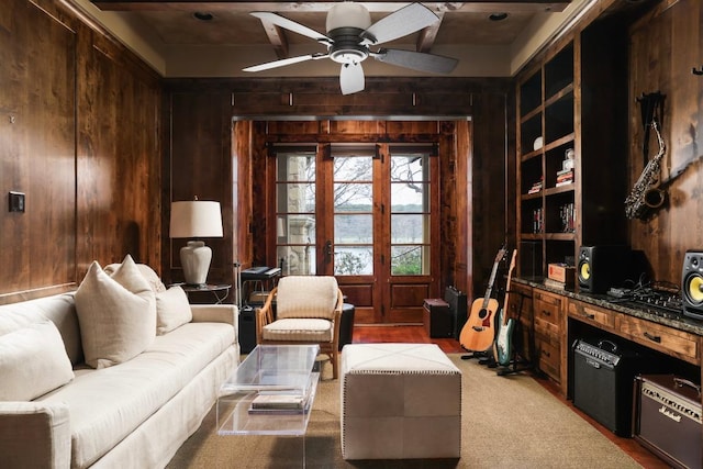 living room with wooden walls, french doors, and ceiling fan