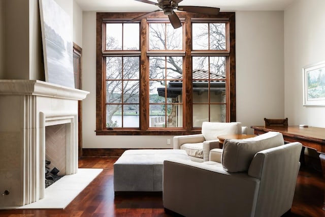 living room with dark wood finished floors, a fireplace with raised hearth, and a healthy amount of sunlight