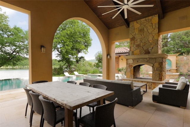 view of patio / terrace featuring an outdoor living space with a fireplace, outdoor dining area, a ceiling fan, and an outdoor pool