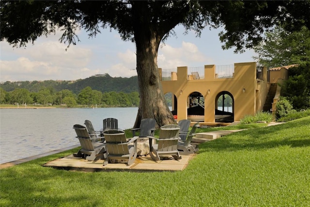 back of property featuring a lawn, a water view, a forest view, and stucco siding