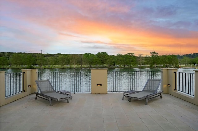 patio terrace at dusk with a balcony and a water view