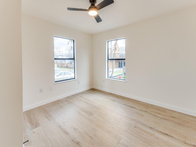 spare room featuring baseboards, light wood finished floors, and ceiling fan