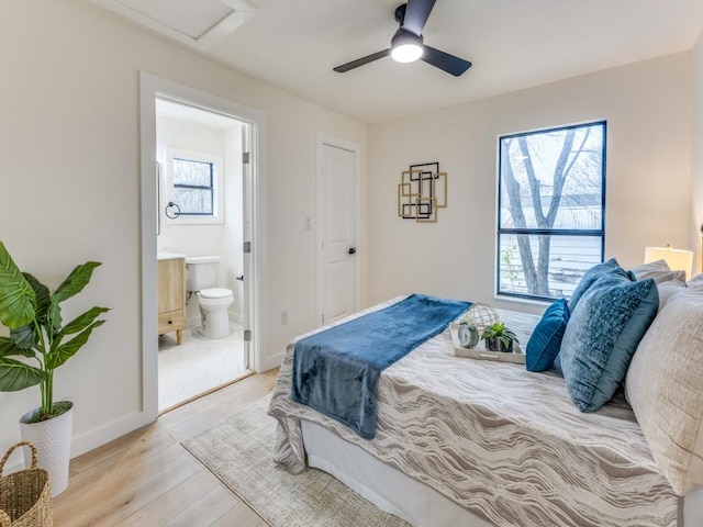 bedroom featuring light wood finished floors, multiple windows, baseboards, and connected bathroom