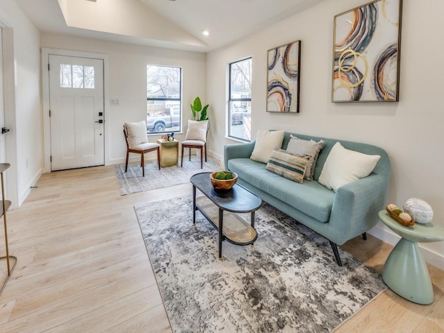 living area featuring lofted ceiling, wood finished floors, and baseboards