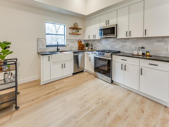 1107 Lincoln St, Austin, TX 78702 - kitchen with appliances with stainless steel finishes, dark countertops, a sink, and light wood finished floors