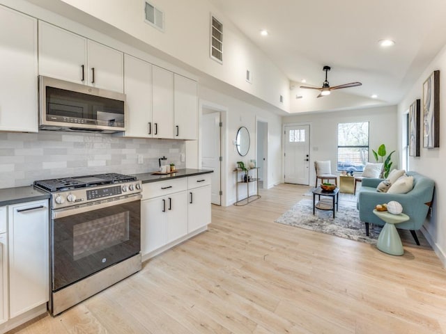 1107 Lincoln St, Austin, TX 78702 - kitchen featuring appliances with stainless steel finishes, dark countertops, ceiling fan, tasteful backsplash, and light wood-style floors