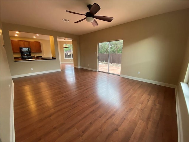 unfurnished living room featuring visible vents, baseboards, ceiling fan, and dark wood finished floors