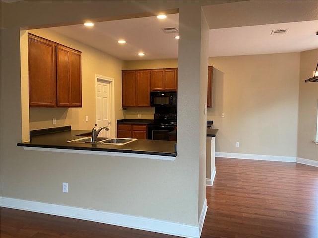 kitchen with baseboards, visible vents, a sink, black appliances, and dark countertops