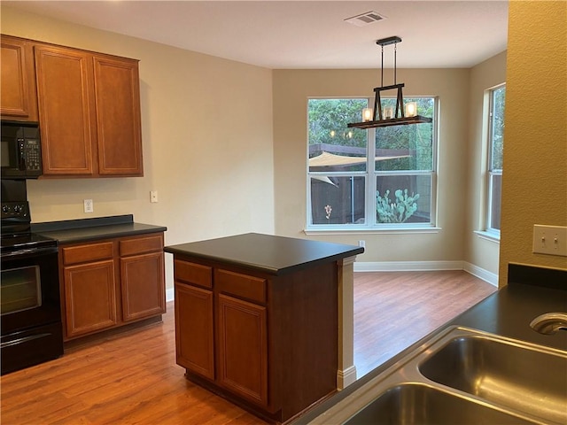 kitchen with visible vents, brown cabinets, black appliances, dark countertops, and wood finished floors