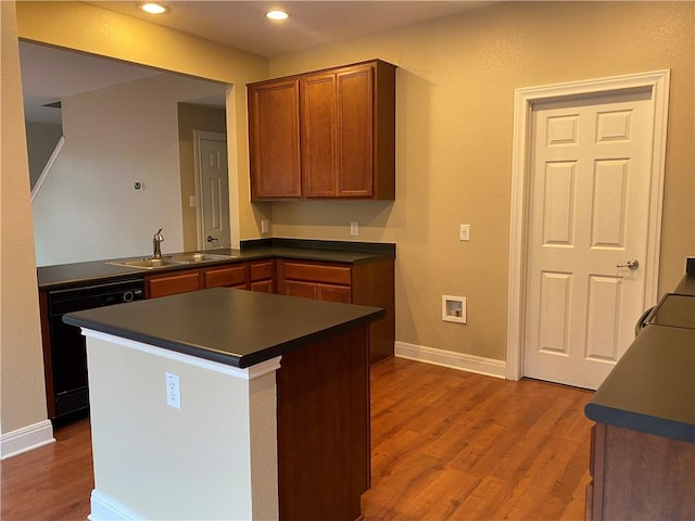 kitchen with dark countertops, dark wood-style floors, dishwasher, and a sink