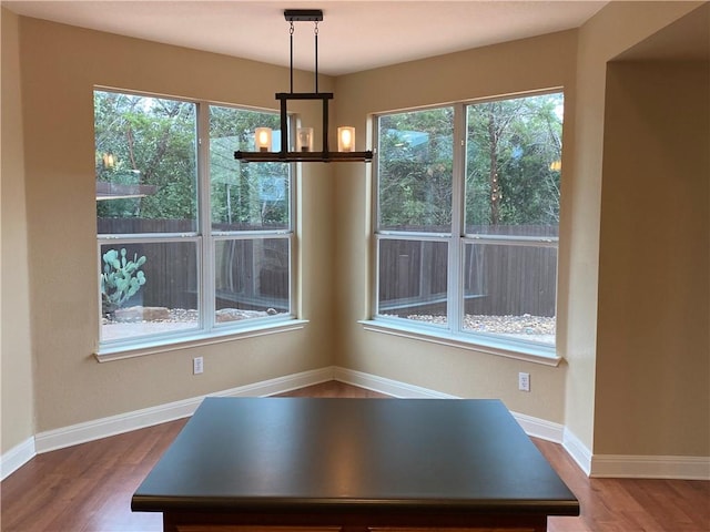 unfurnished dining area with a notable chandelier, baseboards, and wood finished floors