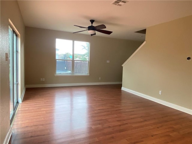 empty room with visible vents, ceiling fan, baseboards, and wood finished floors