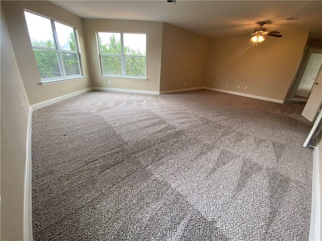 carpeted spare room with ceiling fan and baseboards