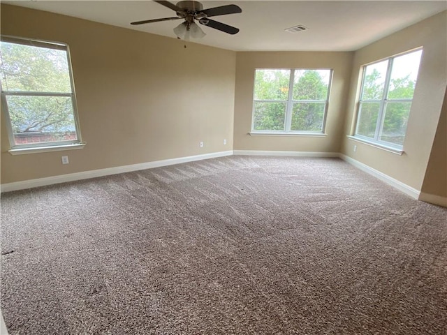 carpeted spare room with visible vents, baseboards, and ceiling fan