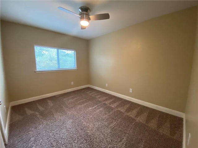 empty room with baseboards, dark carpet, and ceiling fan