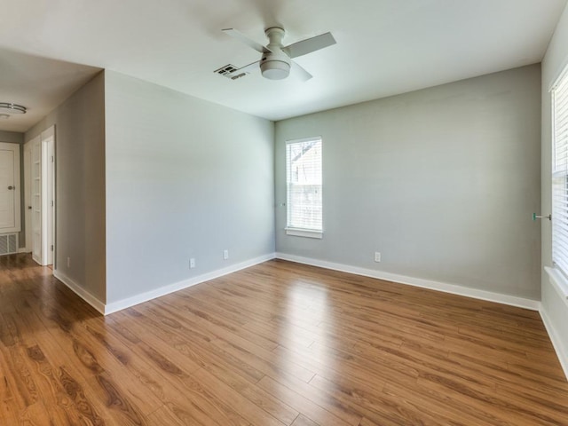 unfurnished room with wood finished floors, visible vents, and baseboards