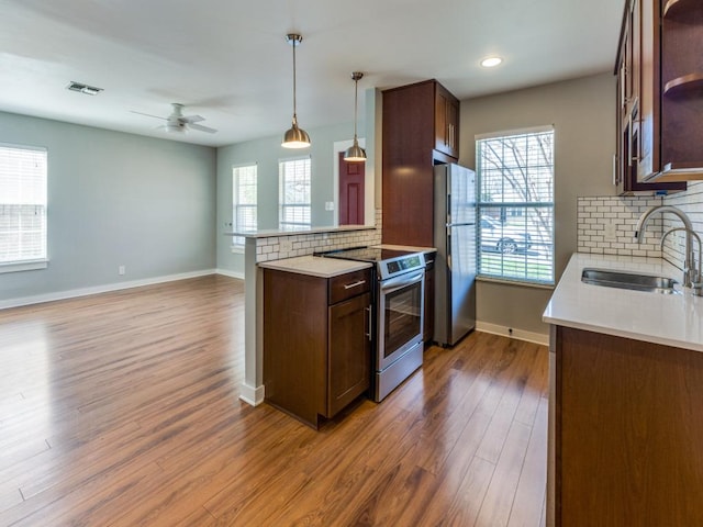 kitchen featuring visible vents, a sink, open shelves, wood finished floors, and appliances with stainless steel finishes