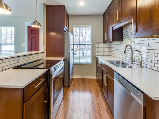 kitchen with stainless steel appliances, light countertops, light wood-style floors, and a sink