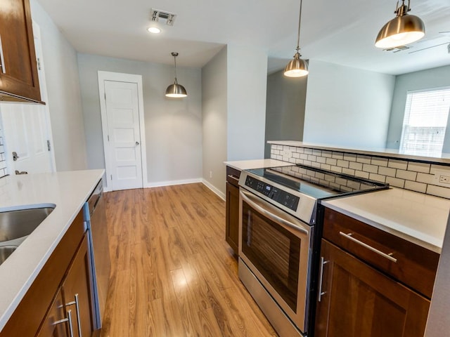 1105 Brookswood Ave, Austin, TX 78721 - kitchen with stainless steel range with electric cooktop, light wood-style flooring, light countertops, pendant lighting, and tasteful backsplash